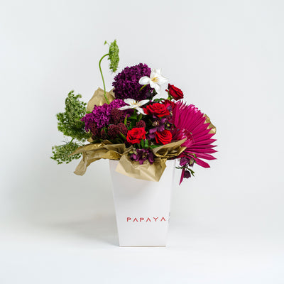 Bouquet of flowers in a white Papaya bag on a light gray background
