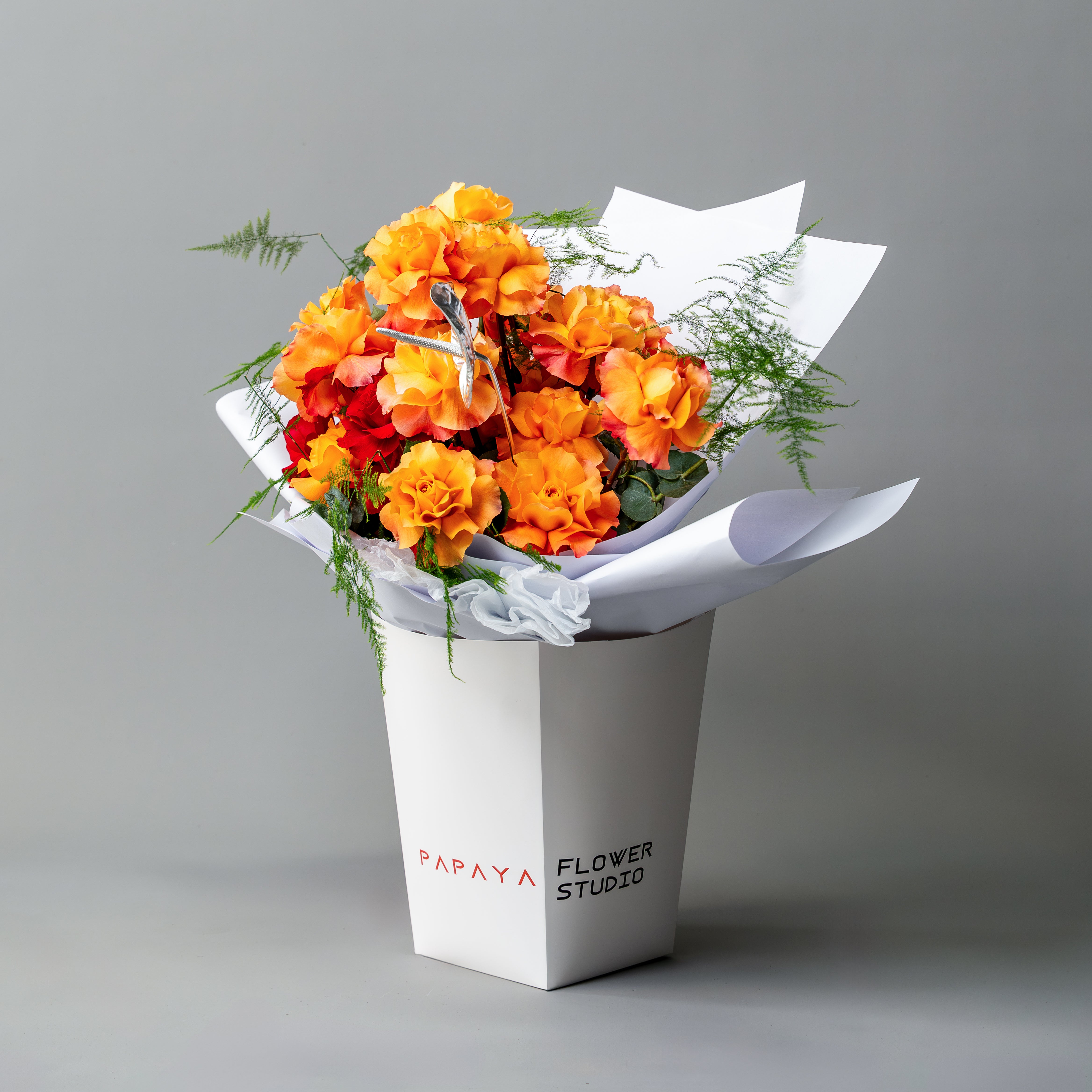Bouquet of orange and red flowers in a white box with 'Papaya Flower Studio' branding on a gray background.