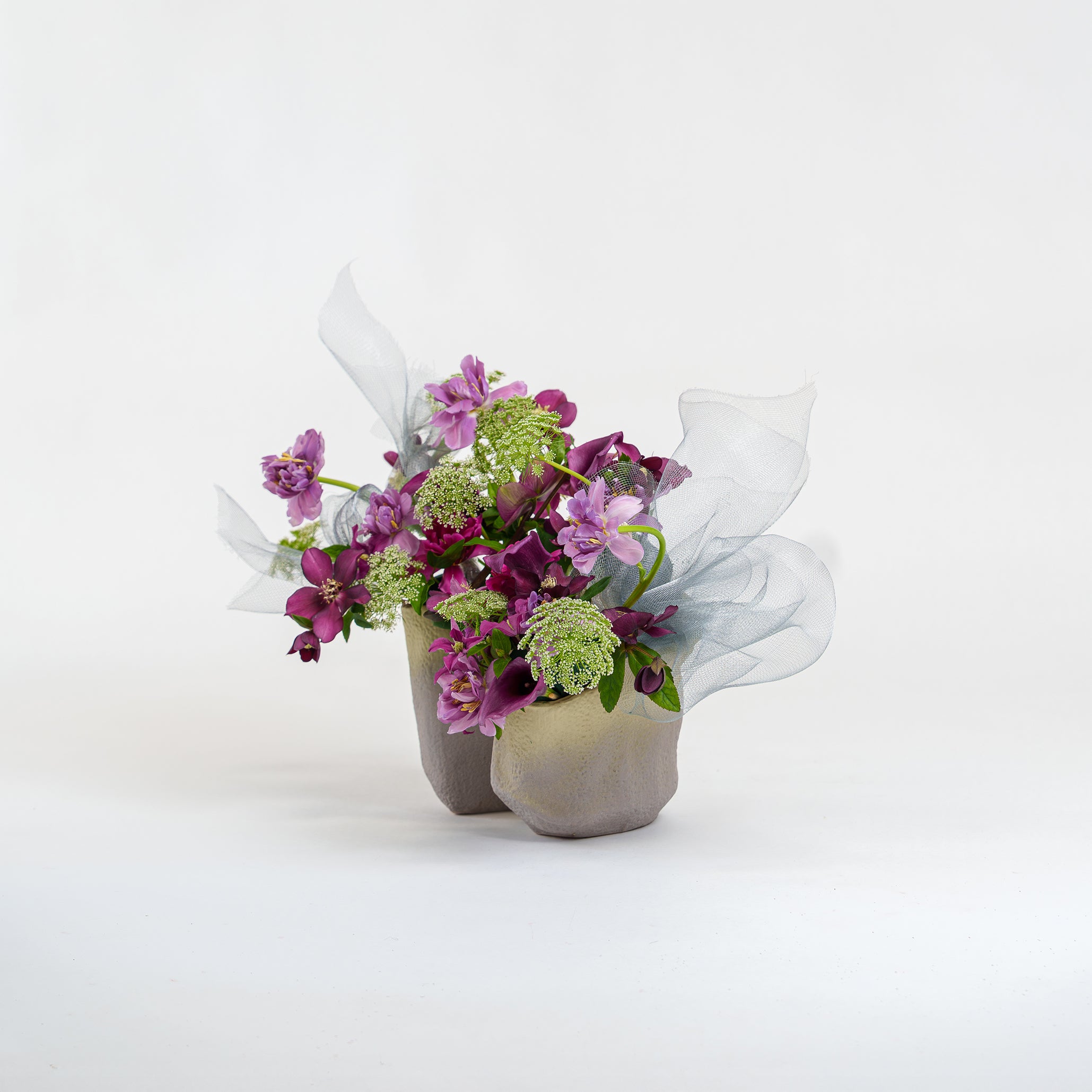 Small bouquet of flowers in a concrete vase on a white background