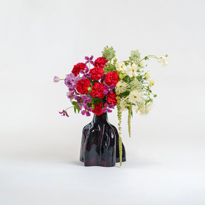 Black vase with colorful flowers on a white background