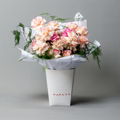Bicolor cream and pink reflexed roses bouquet with silver anthurium leaf in white branded carrier box delivery Dubai.