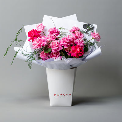 Mixed candy pink and cerise reflexed roses bouquet with silver anthurium leaf in white branded carrier box delivery Dubai.