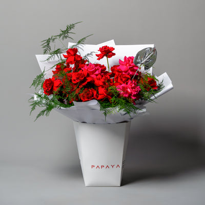 Luxury bouquet of deep red reflexed roses with silver anthurium leaf in white branded carrier box delivery Dubai