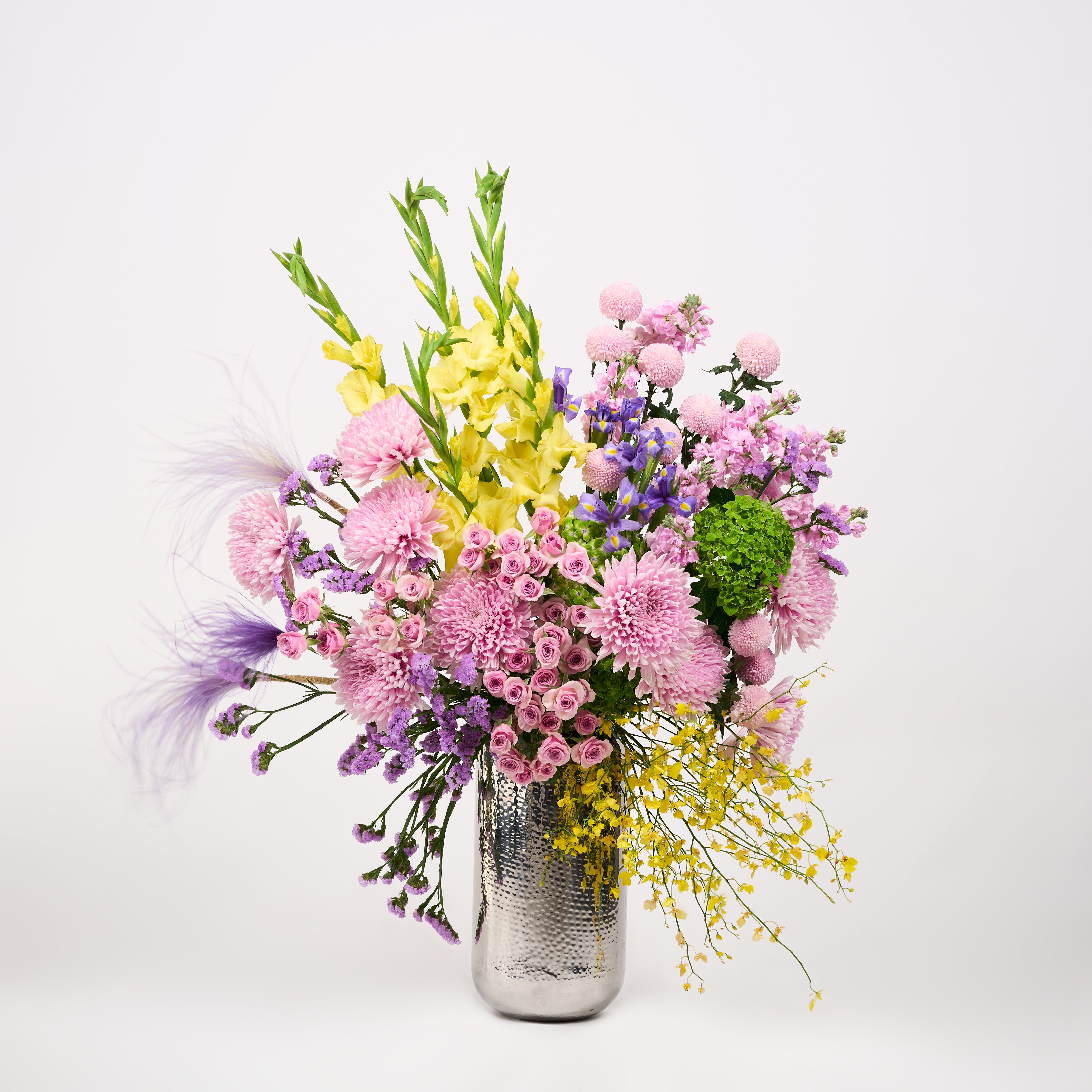 Aria floral arrangement featuring pink roses, rounded pink blooms and purple and yellow flowers.