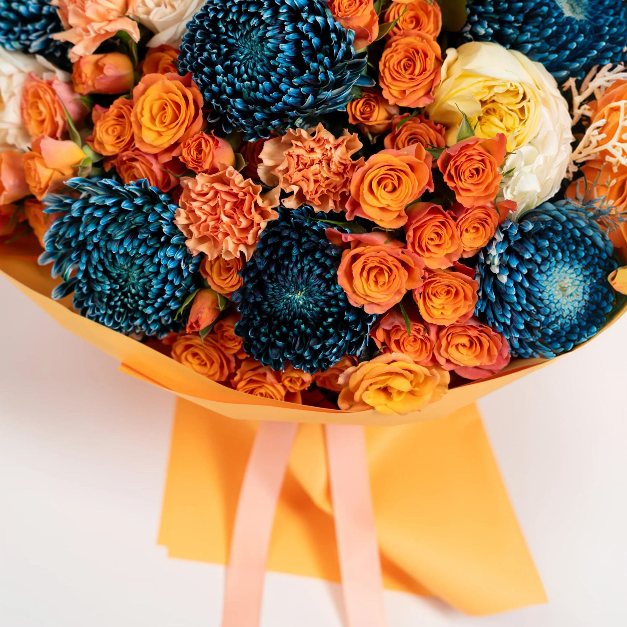 Detailed view of cobalt chrysanthemums and orange spray roses in luxury orange wrapping