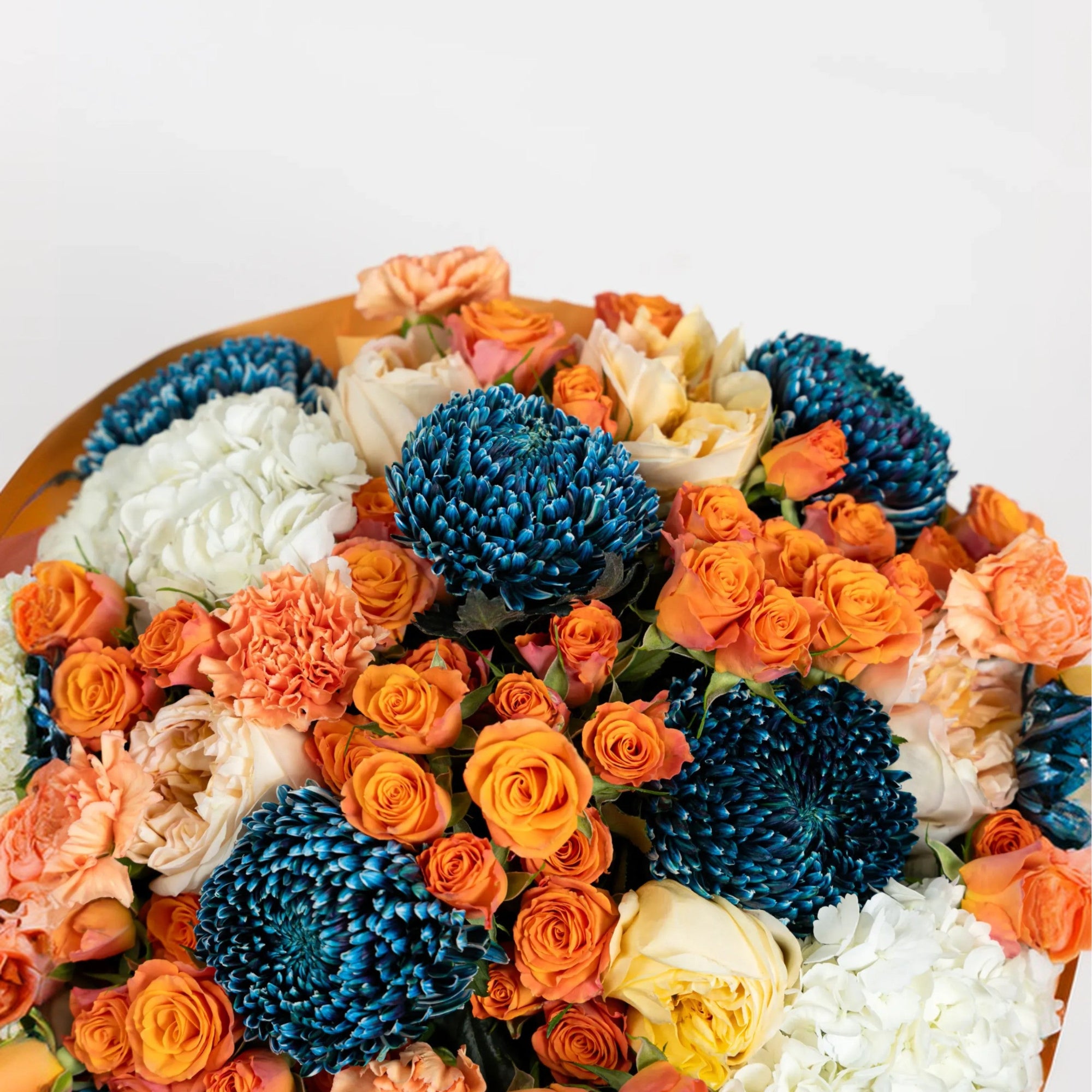 Close-up of cobalt blue chrysanthemums, orange roses, peach carnations and ivory flowers
