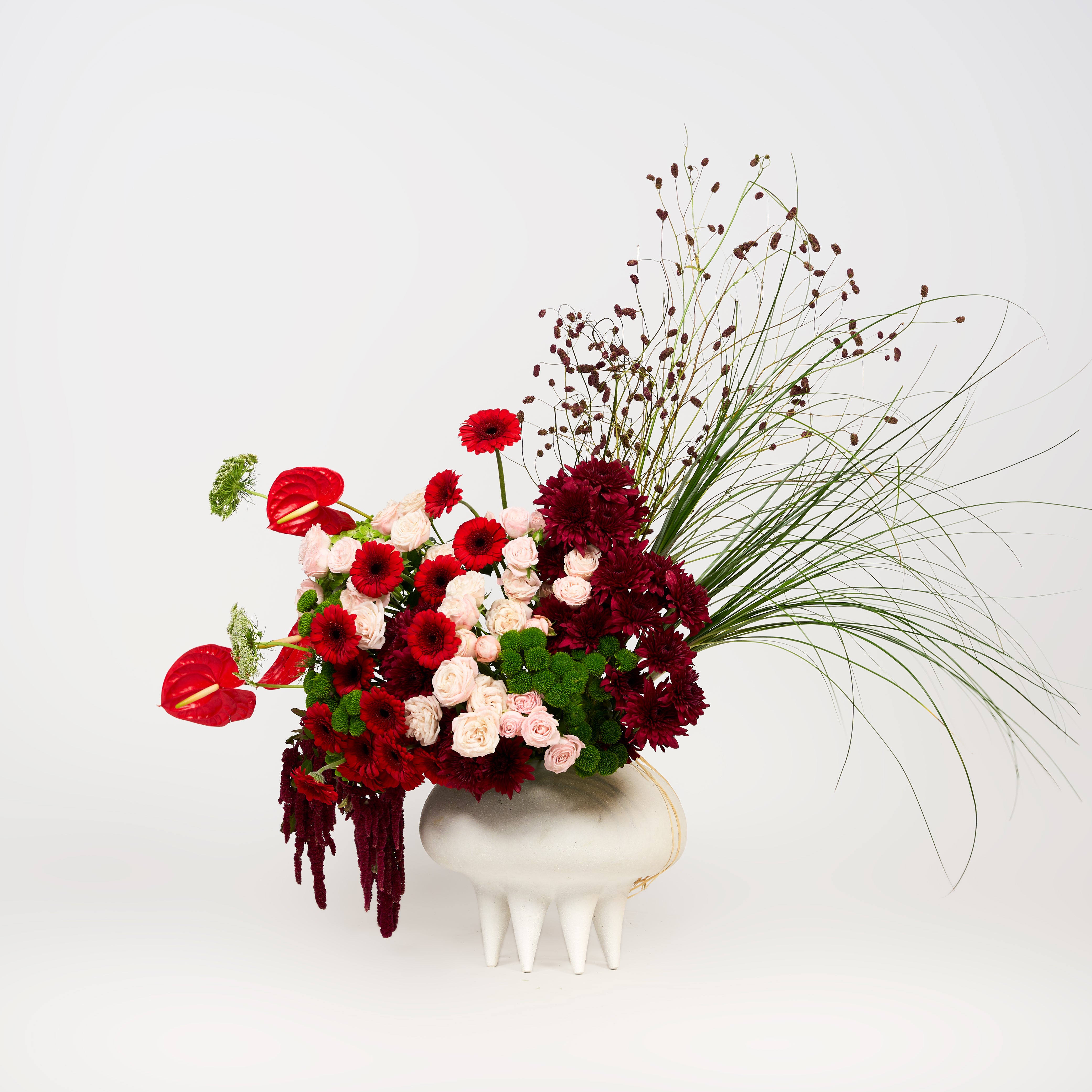 Rosalia floral arrangement featuring red blooms, pale pink roses, burgundy flowers and green foliage