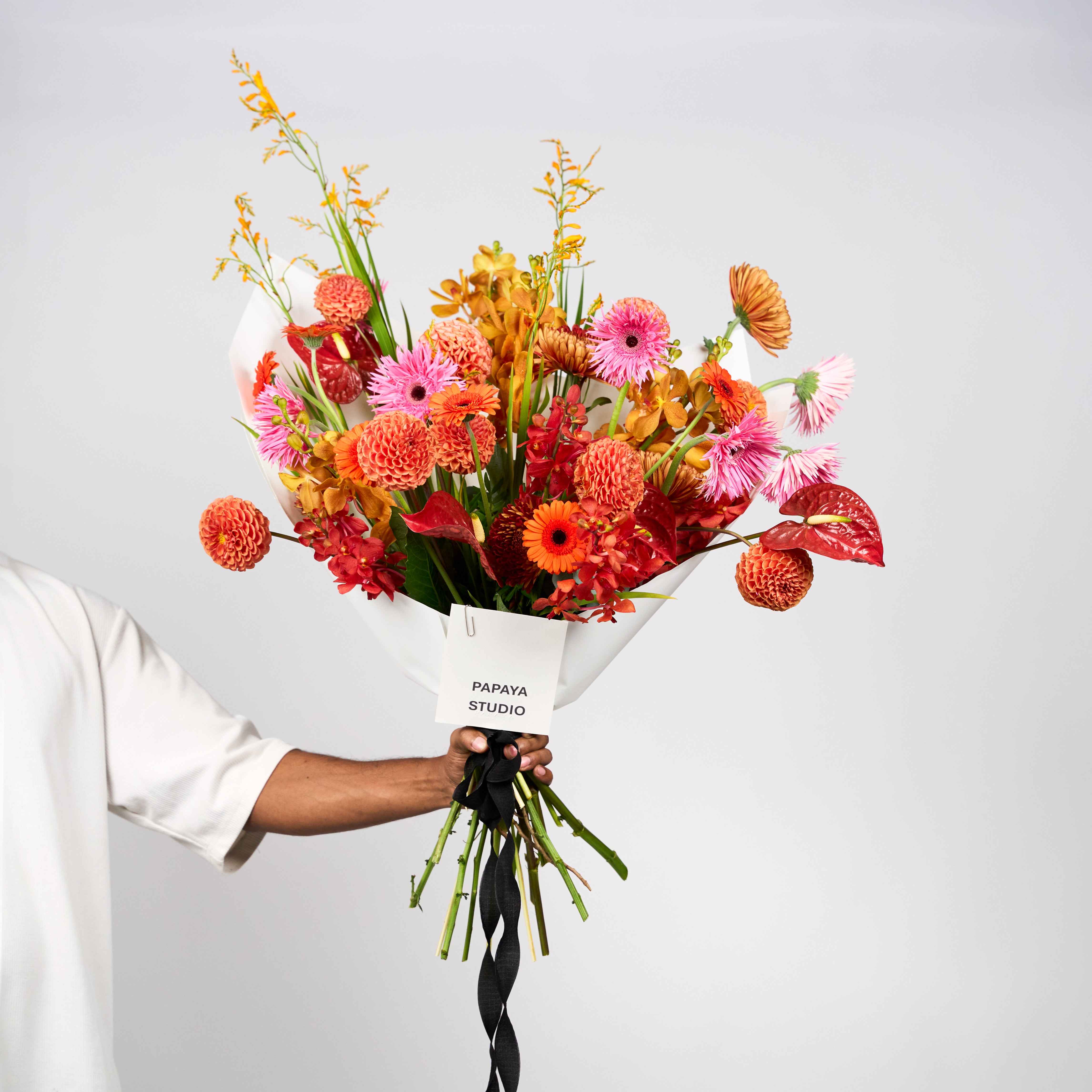 Saffron Kiss bouquet featuring orange and coral blooms with pink flowers and fresh green foliage