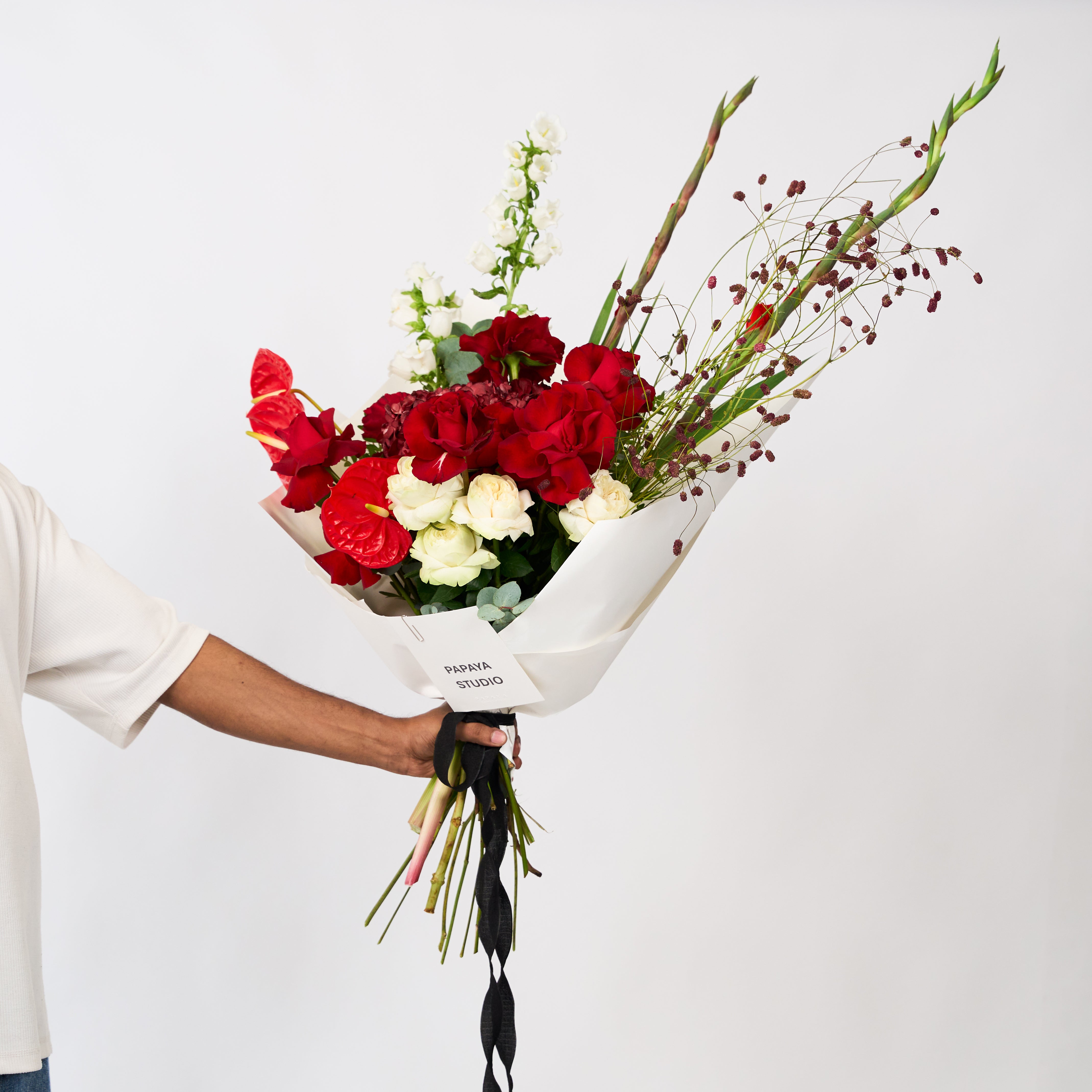 Scarlet Promise bouquet featuring red roses, creamy ivory blooms and deep burgundy floral accents.
