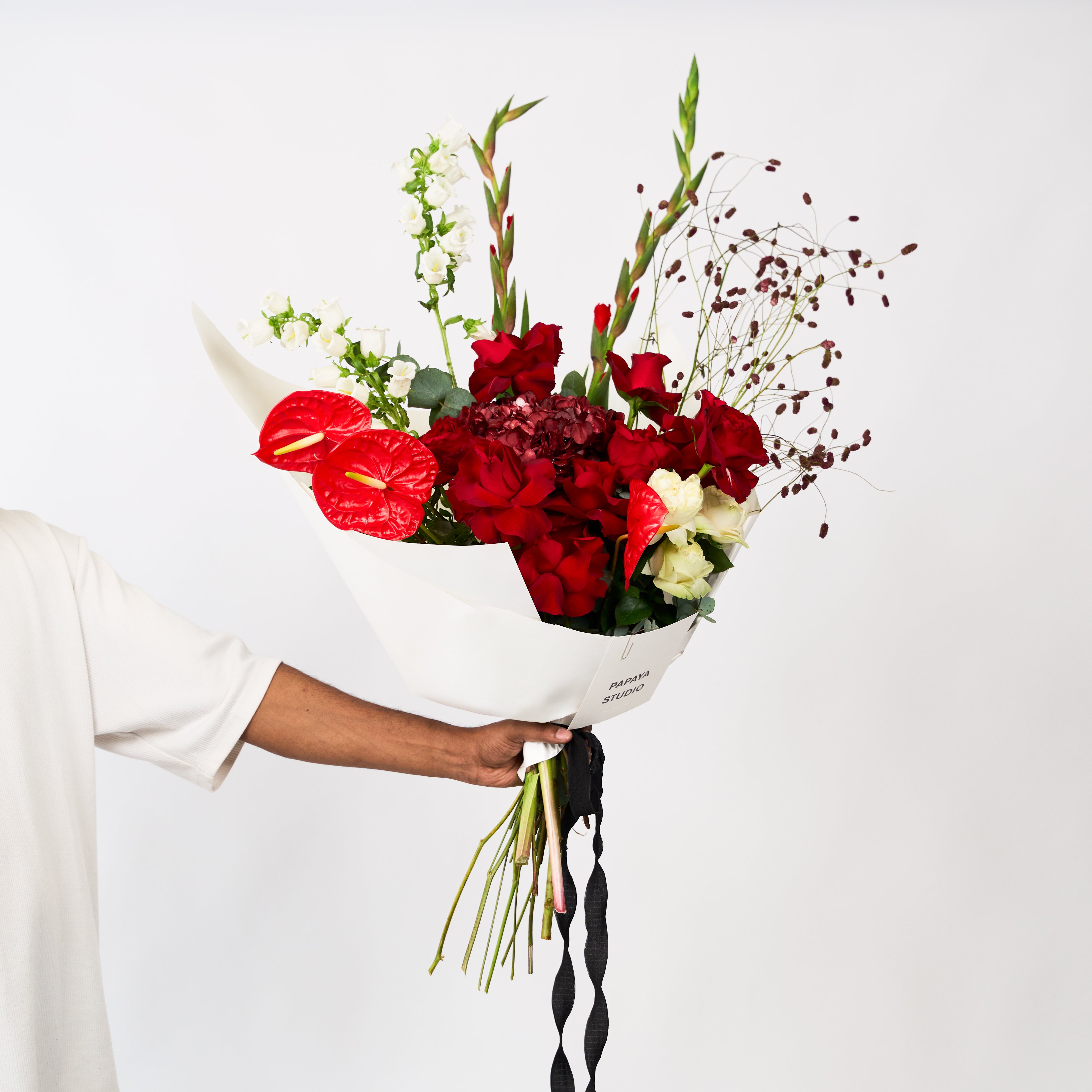 Mixed red and ivory flowers with burgundy accents in Papaya Flower Studio’s Scarlet Promise bouquet.
