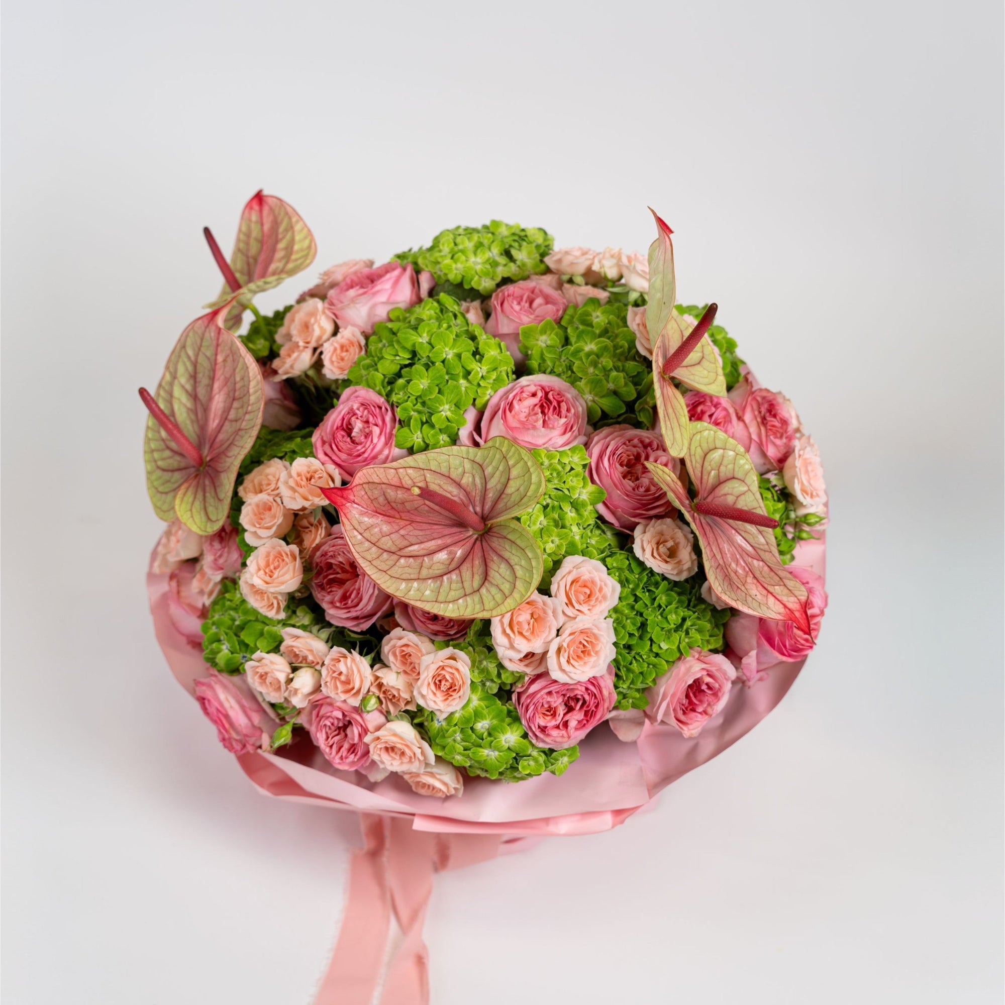 Top view of pink anthuriums, garden roses, peach spray roses and green hydrangeas in The Eden Affair