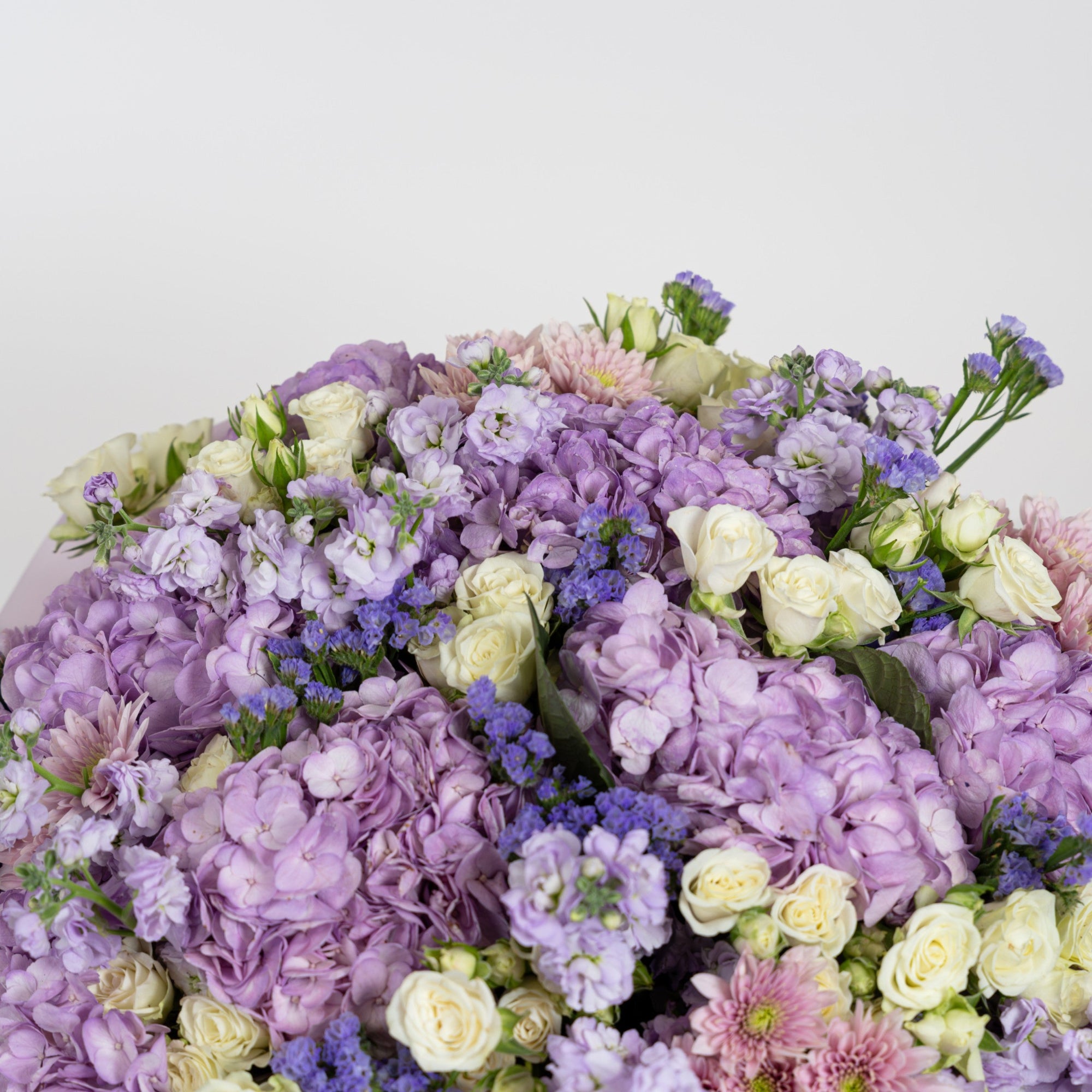 Close-up of lavender hydrangeas, stock flowers, violet limonium and ivory spray roses