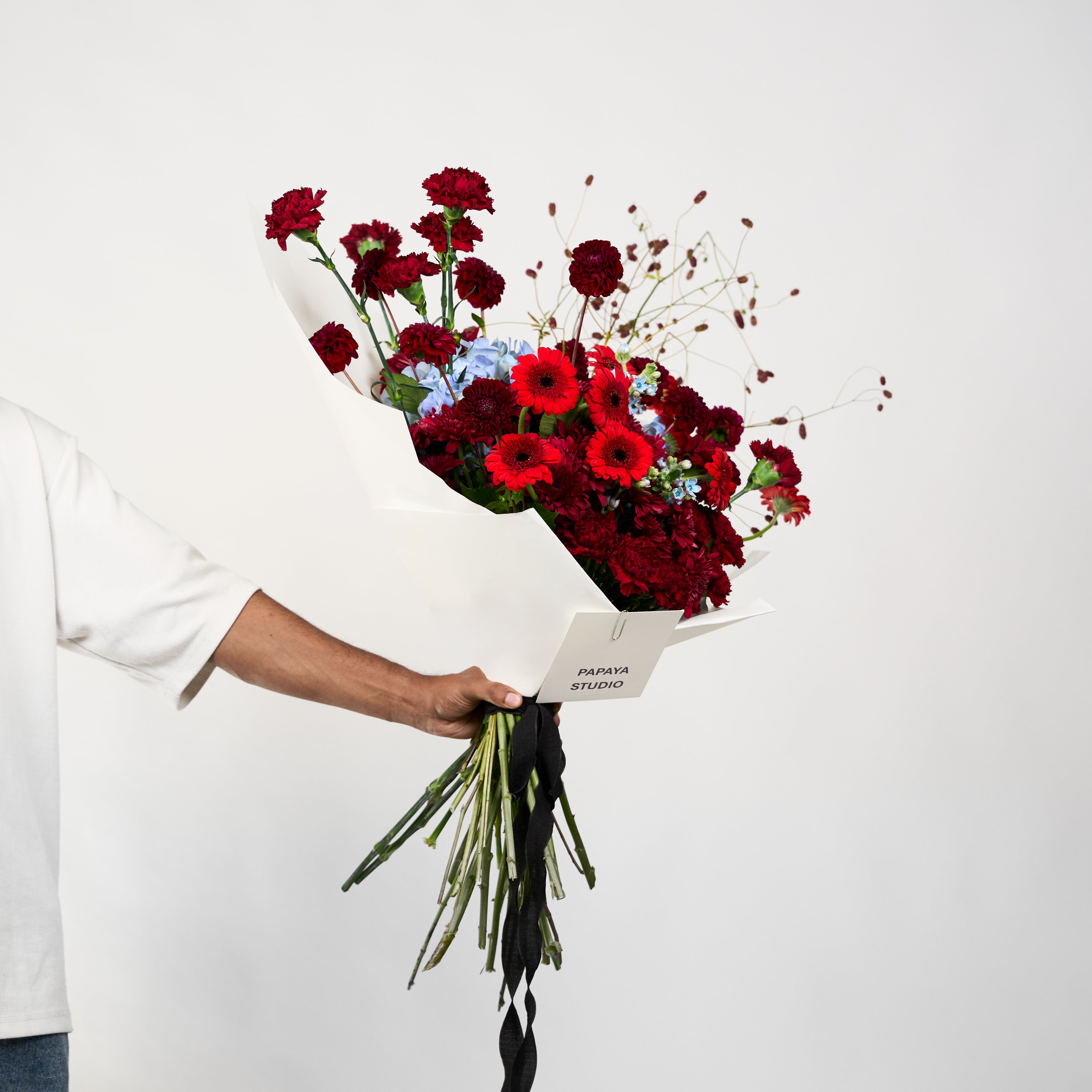 Velvet Affair bouquet featuring rich red and burgundy blooms with soft blue floral accents.