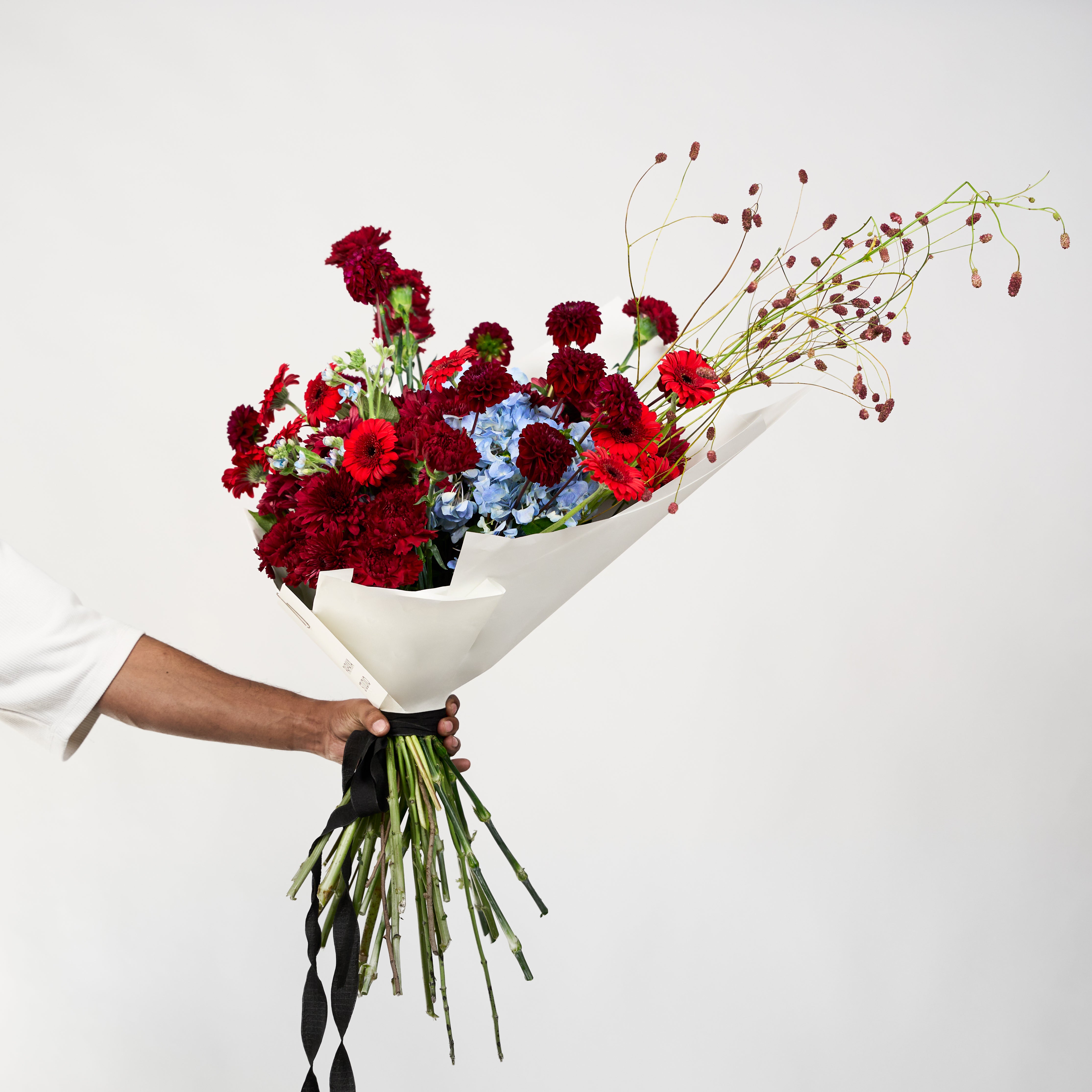 Mixed red, burgundy and pale blue flowers in Papaya Flower Studio’s Velvet Affair bouquet.
