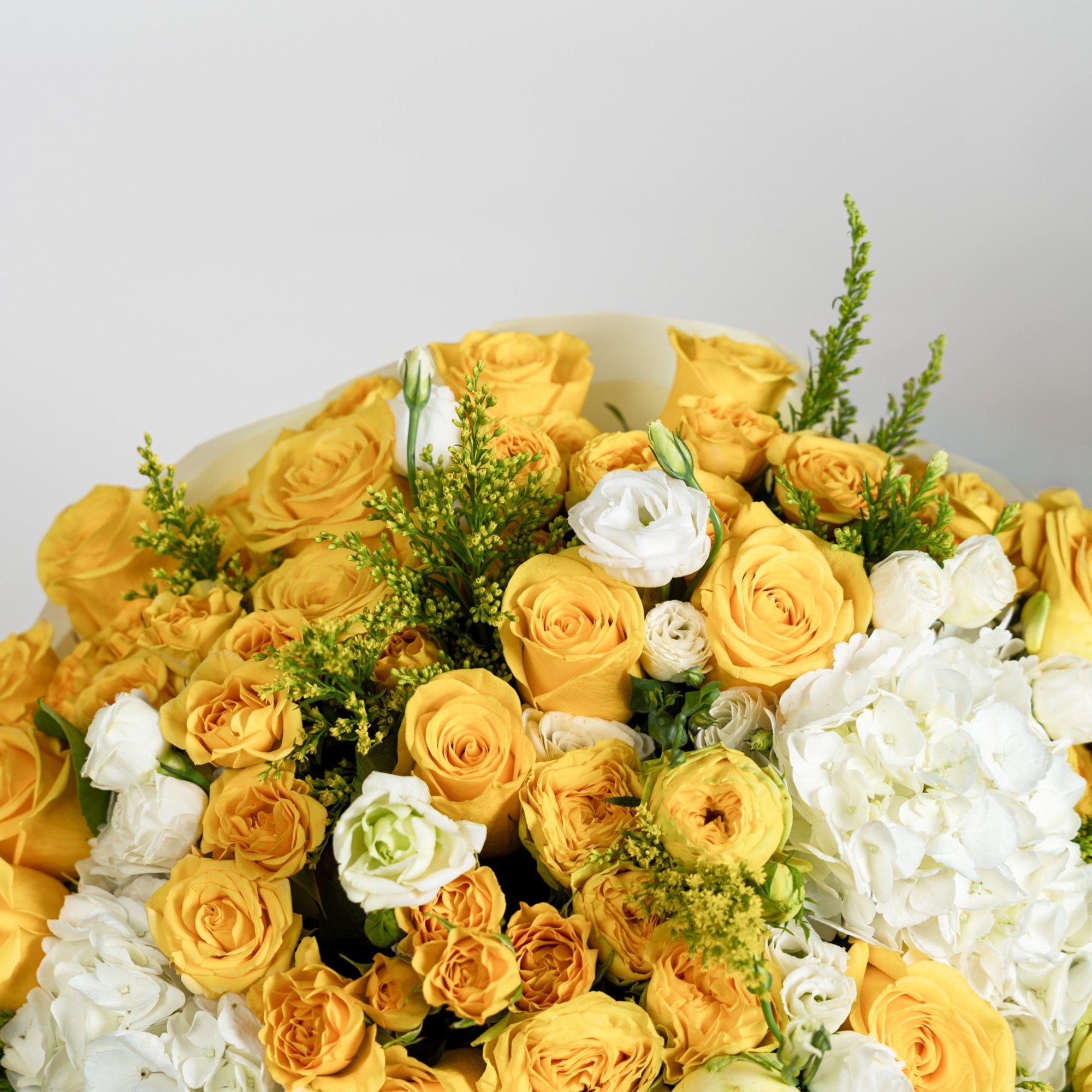 Close-up of yellow roses, white lisianthus, white hydrangeas and golden solidago